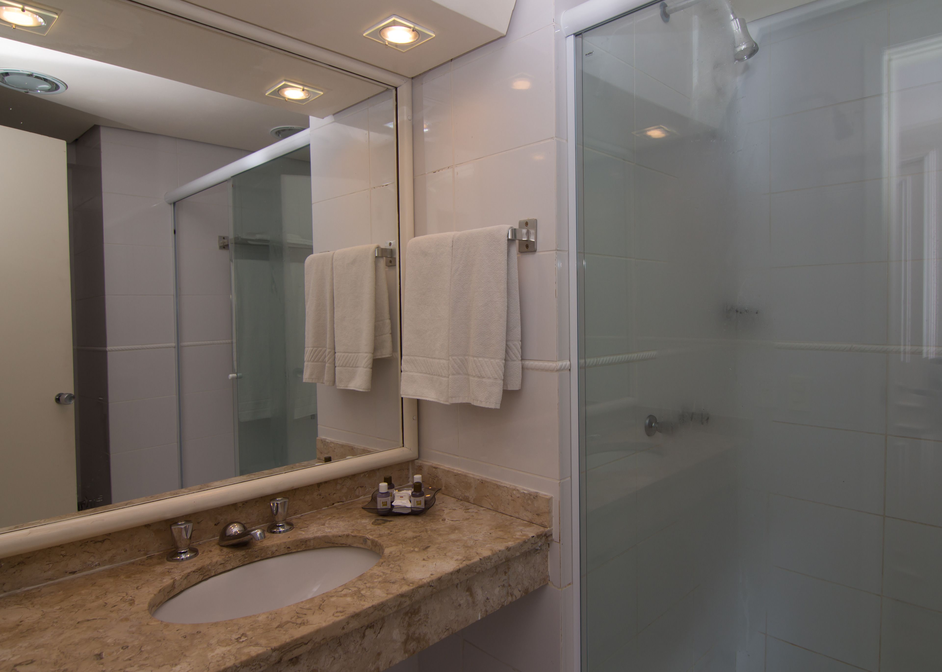 A bathroom with a marble sink, a glass shower enclosure, and a large mirror.