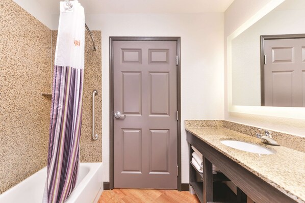 A bathroom with a shower, a door, a sink, and a mirror.