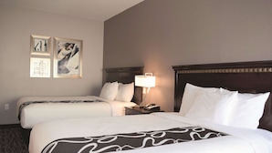Een hotelkamer met twee bedden, een nachtkastje met een lamp en kunst aan de muur.