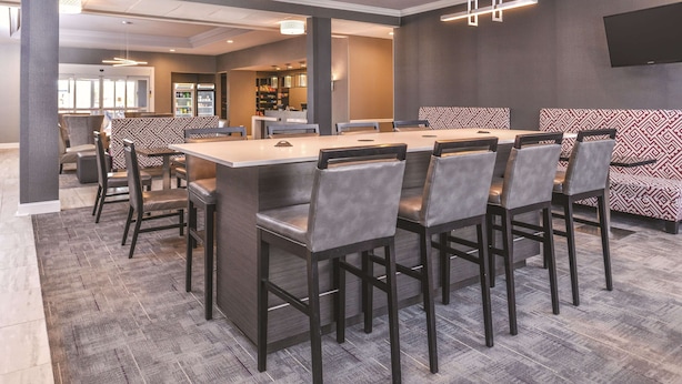 Een moderne vergaderzaal met een lange tafel, zes stoelen en een barruimte met zitplaatsen.