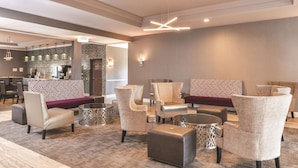 Een lobby met een zithoek, inclusief gestreepte stoelen en poefs, een koffiebar en een receptiebalie.