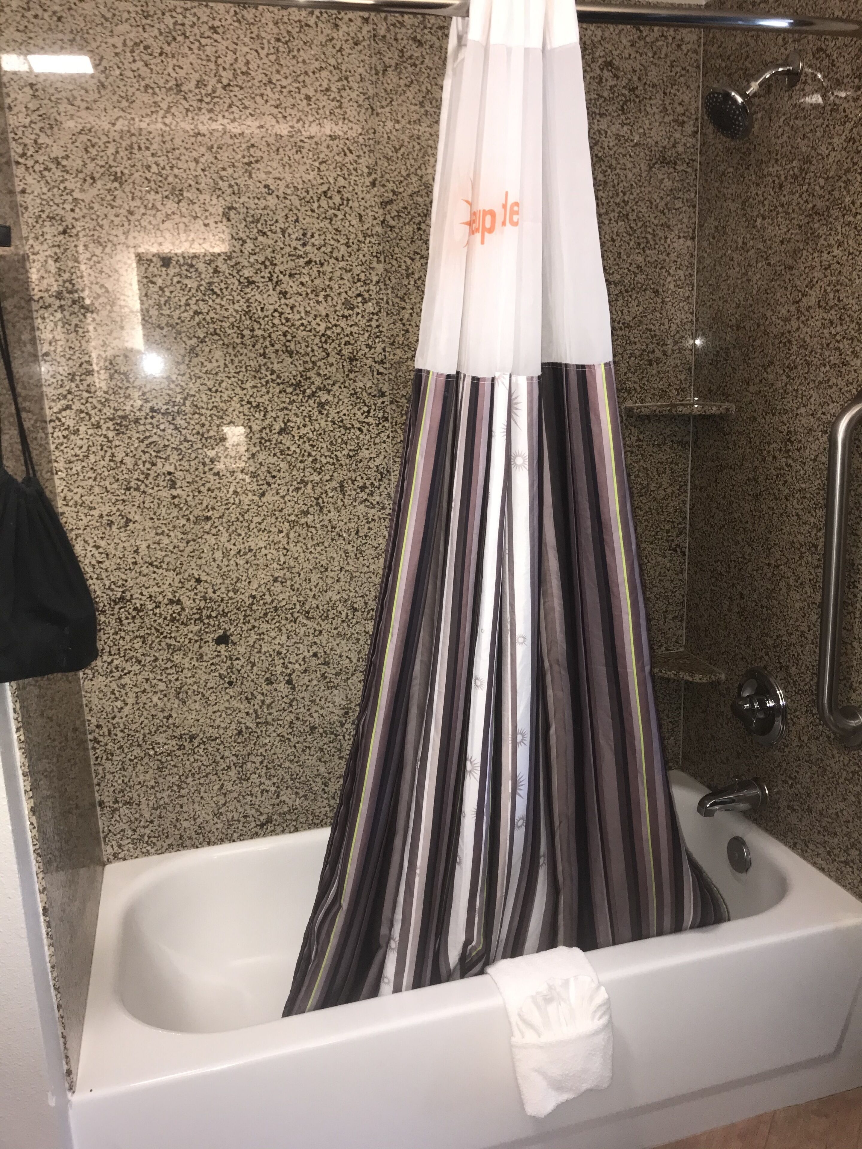Un baño con bañera, ducha y pared revestida de granito.