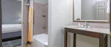 Un baño con ducha, lavabo y espejo.
