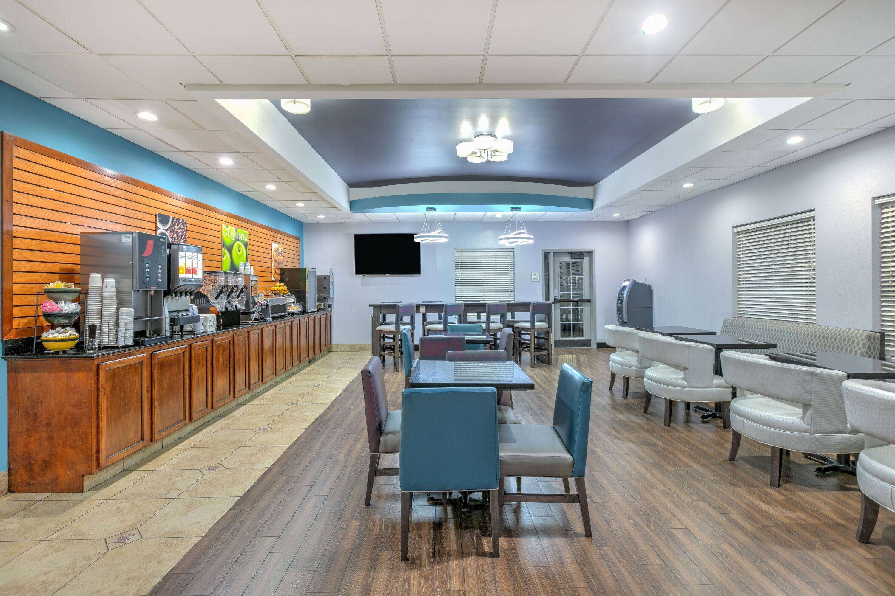 A modern restaurant with a long counter, multiple seating options including booths and tables, and a variety of food and drink dispensers.