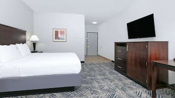 Una habitación de hotel con cama, escritorio, televisor, armario y puerta.