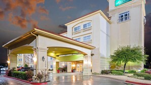 A hotel with a prominent entrance, a balcony, and a sign indicating it is a La Quinta Inn & Suites.