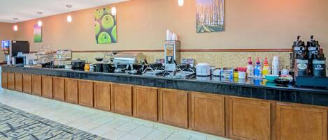 A hotel reception area with a long counter, coffee machines, and various food service equipment.