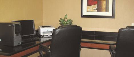 A hotel office with a desktop computer, printer, and two office chairs.