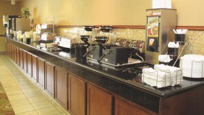 A buffet setup with coffee machines, a beverage dispenser, and a salad bar.