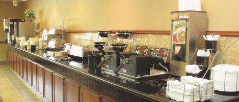 Un montaje tipo bufé con máquinas de café, dispensador de bebidas y una barra de ensaladas.