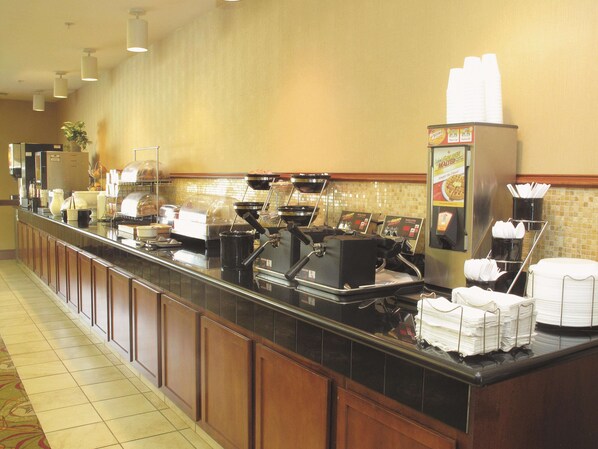 A buffet setup with coffee machines, a beverage dispenser, and a salad bar.
