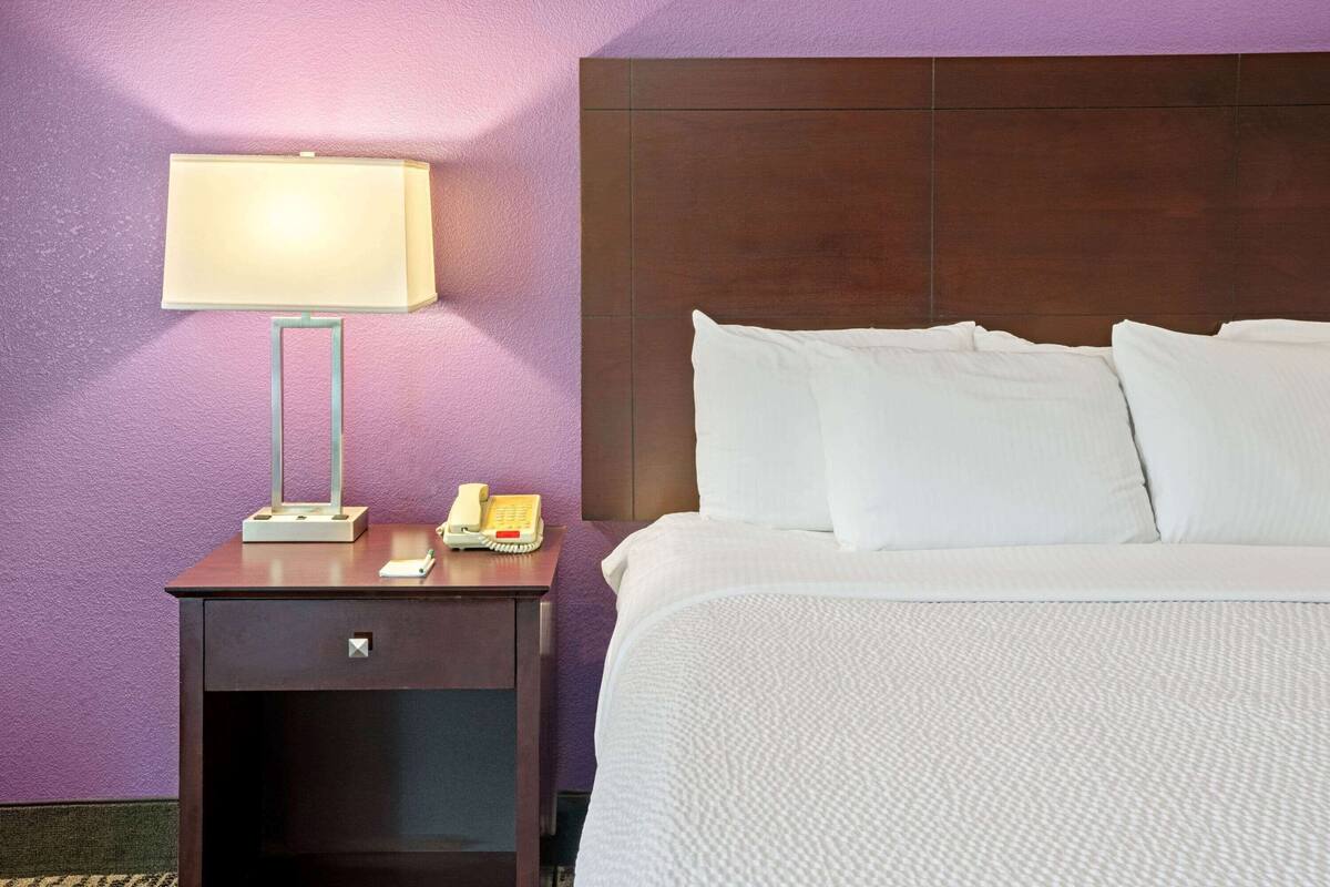 A hotel room with a bed, a nightstand with a lamp, and a telephone.