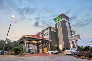 A hotel with a modern design, featuring a covered entrance and multiple parking spaces. - La Quinta Inn & Suites by Wyndham Houston - Magnolia (Magnolia)