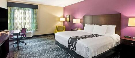 Una habitación de hotel con una cama grande, un escritorio, una silla y un televisor.
