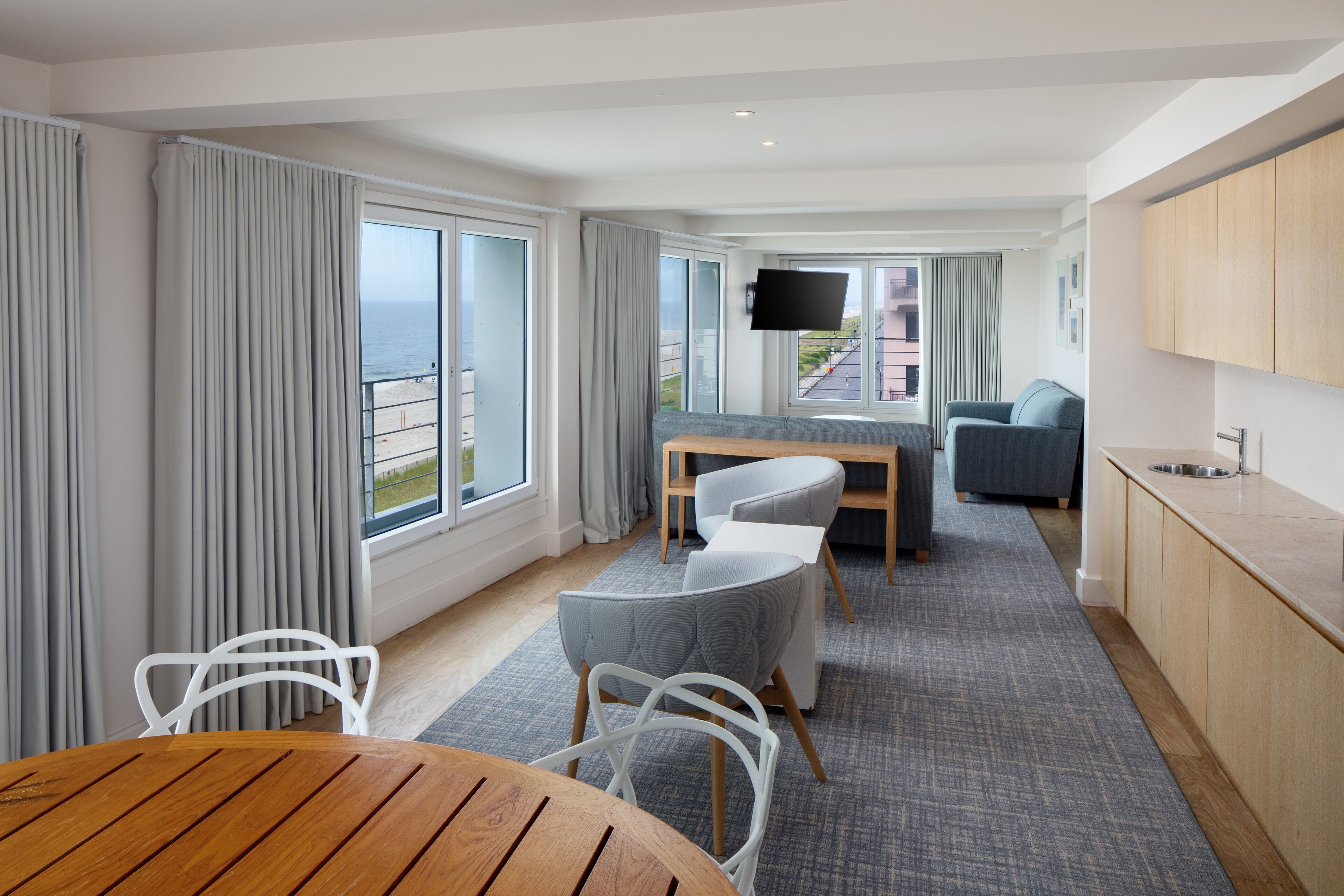 A modern hotel room with a balcony, a dining area, a sofa, and a TV. - Allegria Hotel (Long Beach)