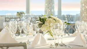 A table set for a formal event with clear glassware, white napkins, and a floral centerpiece. - Allegria Hotel (Long Beach)