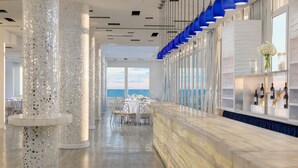 A modern bar area with a marble countertop, decorative pillars, and a view of the sea. - Allegria Hotel (Long Beach)
