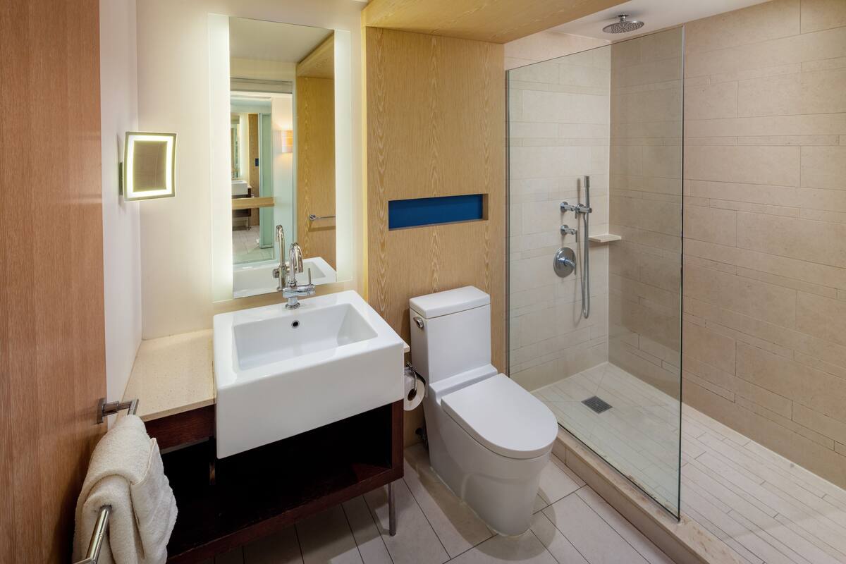 Un baño moderno con lavamanos, inodoro y ducha con mampara de vidrio.