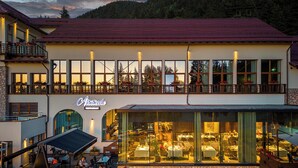 A two-story building with a restaurant on the ground floor and a balcony with outdoor seating. - Ana Hotels Sport Poiana Brasov (Brasov)