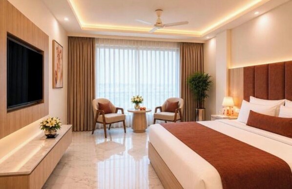 A hotel room with a large bed, two armchairs, a small table with flowers, a TV, and a ceiling fan. - Hotel Vishal Residency, Mahipalpur Near IGI Delhi Airport (New Delhi)
