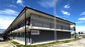 A two-story building with a sign indicating an office on the ground floor. - Briarwood Motel Near Valdosta University I 75 (Valdosta)