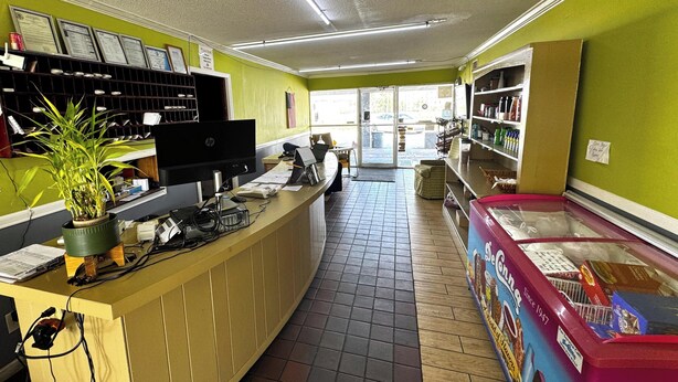 A counter with a computer, a plant, and a freezer with De'Gennia branding. - Briarwood Motel Near Valdosta University I 75 (Valdosta)