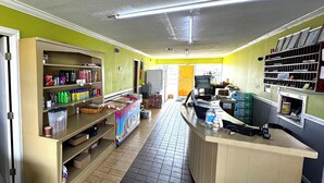 A clean, well-organized room with a reception desk, shelves with various items, and a tiled floor. - Briarwood Motel Near Valdosta University I 75 (Valdosta)