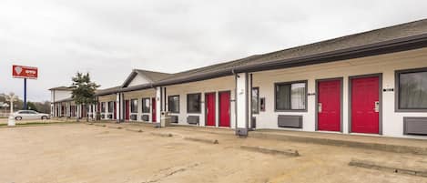 A motel with multiple red doors and a parking lot.