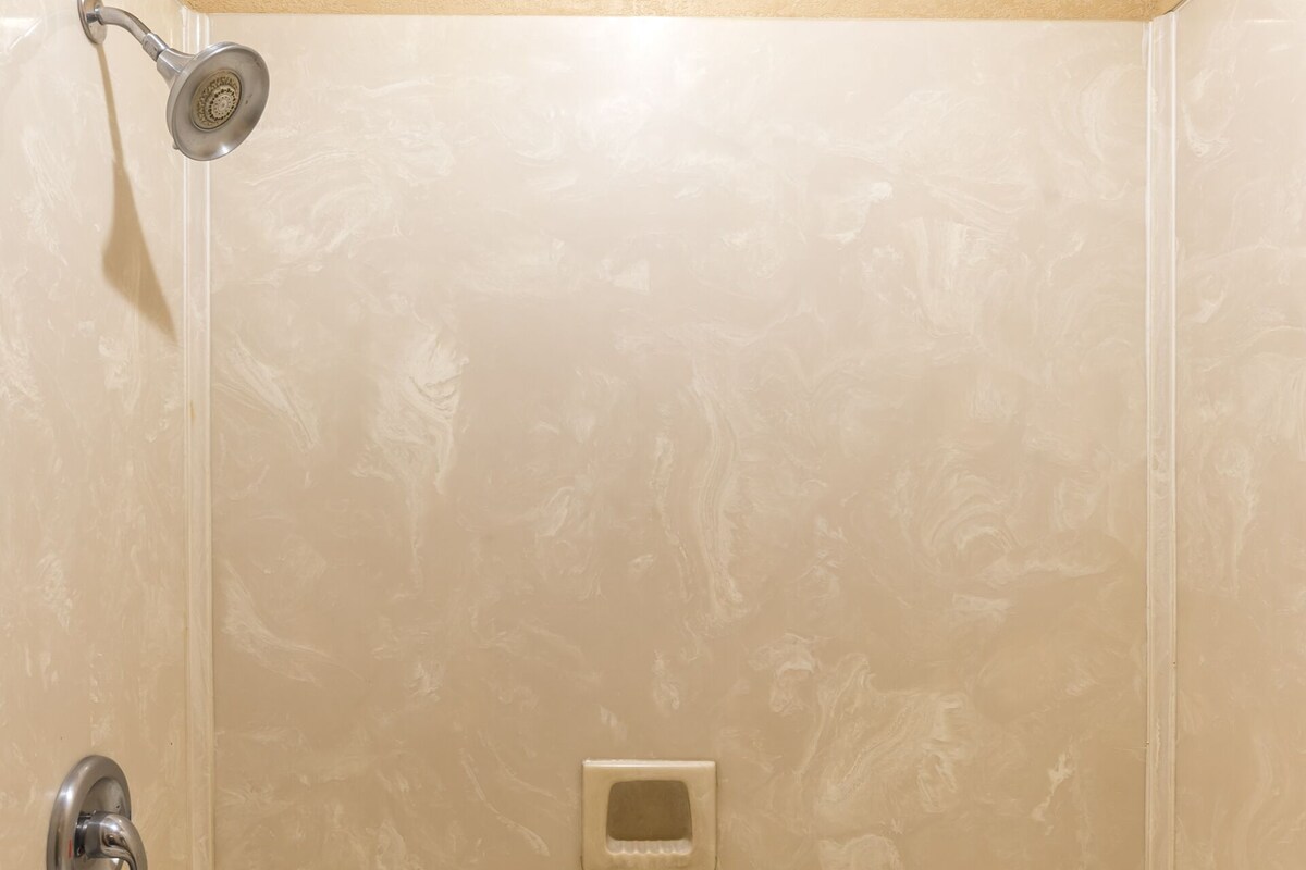 A bathroom with a bathtub, a showerhead, and a towel rack.