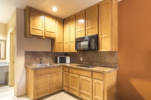 Una cocina con armarios de madera, microondas y lavamanos.