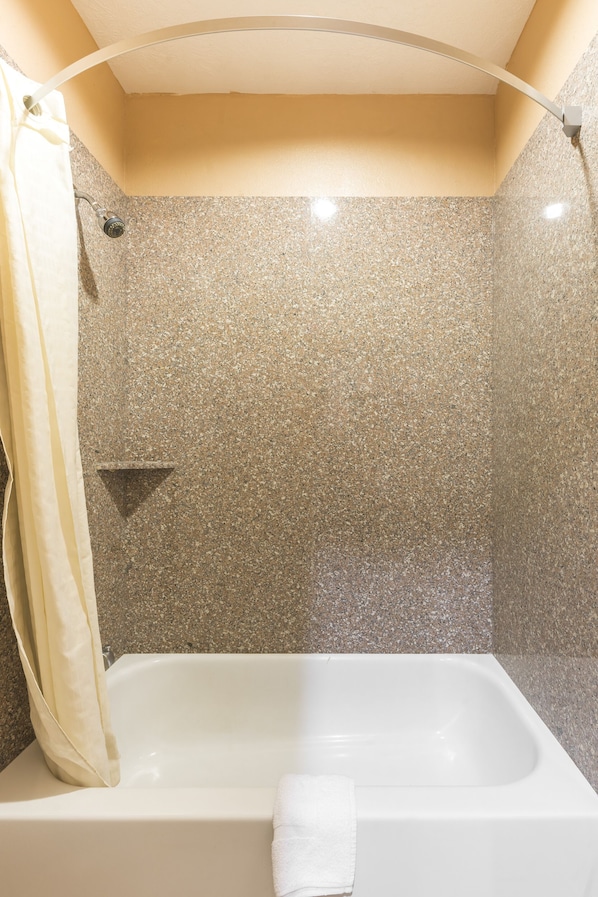 Un baño con ducha, bañera y una toalla colgada en la pared.