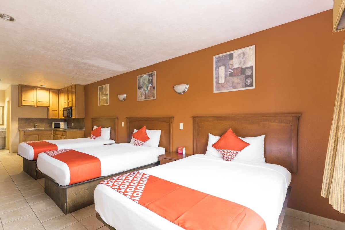 A hotel room with two beds, a kitchenette, and artwork on the walls.