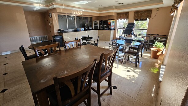 Un comedor amplio con una gran mesa de madera y sillas, una zona de cocina con mostrador y electrodomésticos, y vistas al exterior.