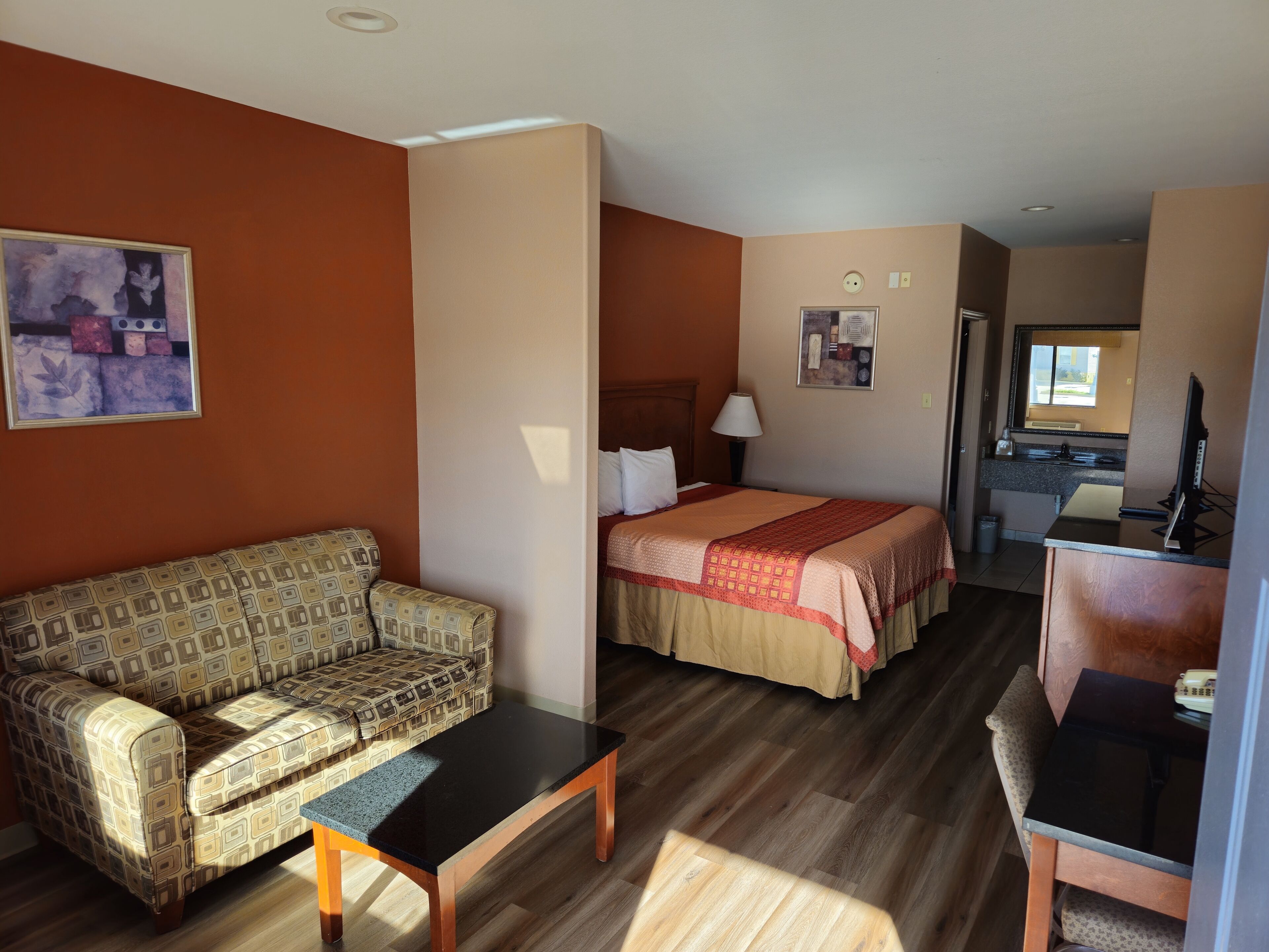 Une chambre d’hôtel équipée d’un canapé, d’un lit, d’un bureau et d’une kitchenette.