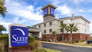 Edifício Sleep Inn & Suites com placa visível, fachada de tijolos e torre com sinalização.