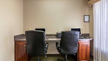 A hotel office with two desks, each with a computer and chair, and a small cabinet.