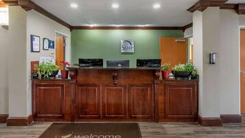 A reception desk with a 'Sleep In Suites' sign, framed certificates, and potted plants.