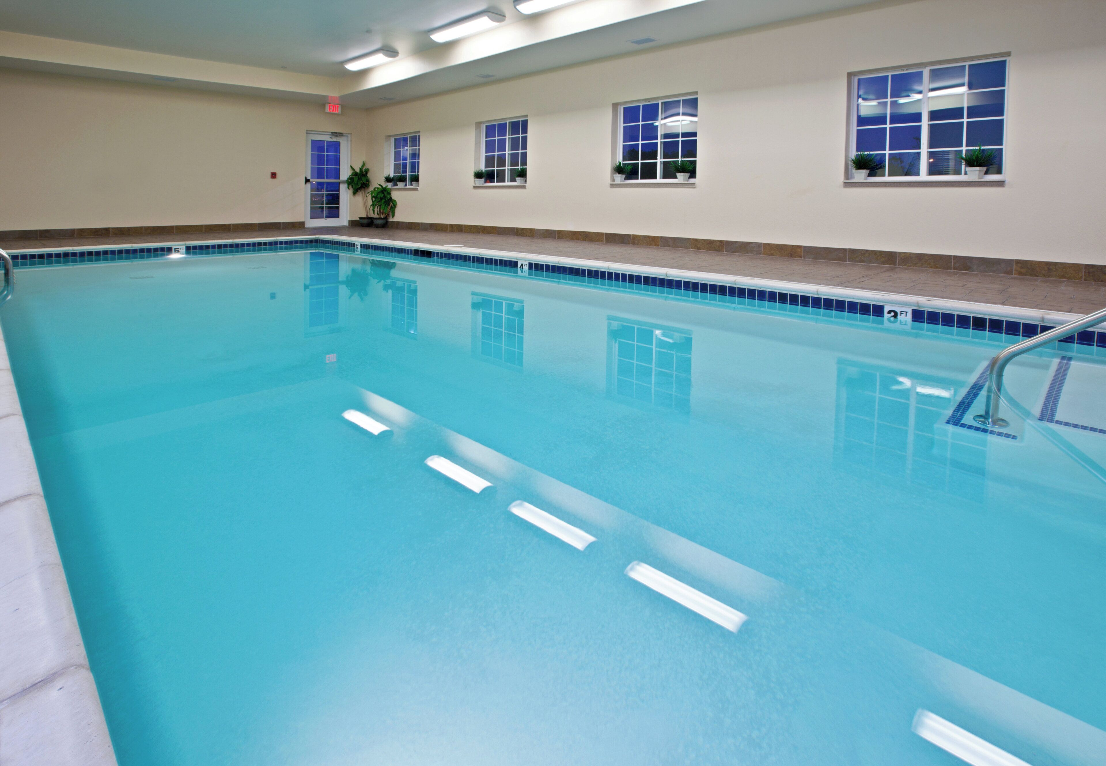 A large indoor swimming pool with clear blue water, multiple lanes, and safety markings.
