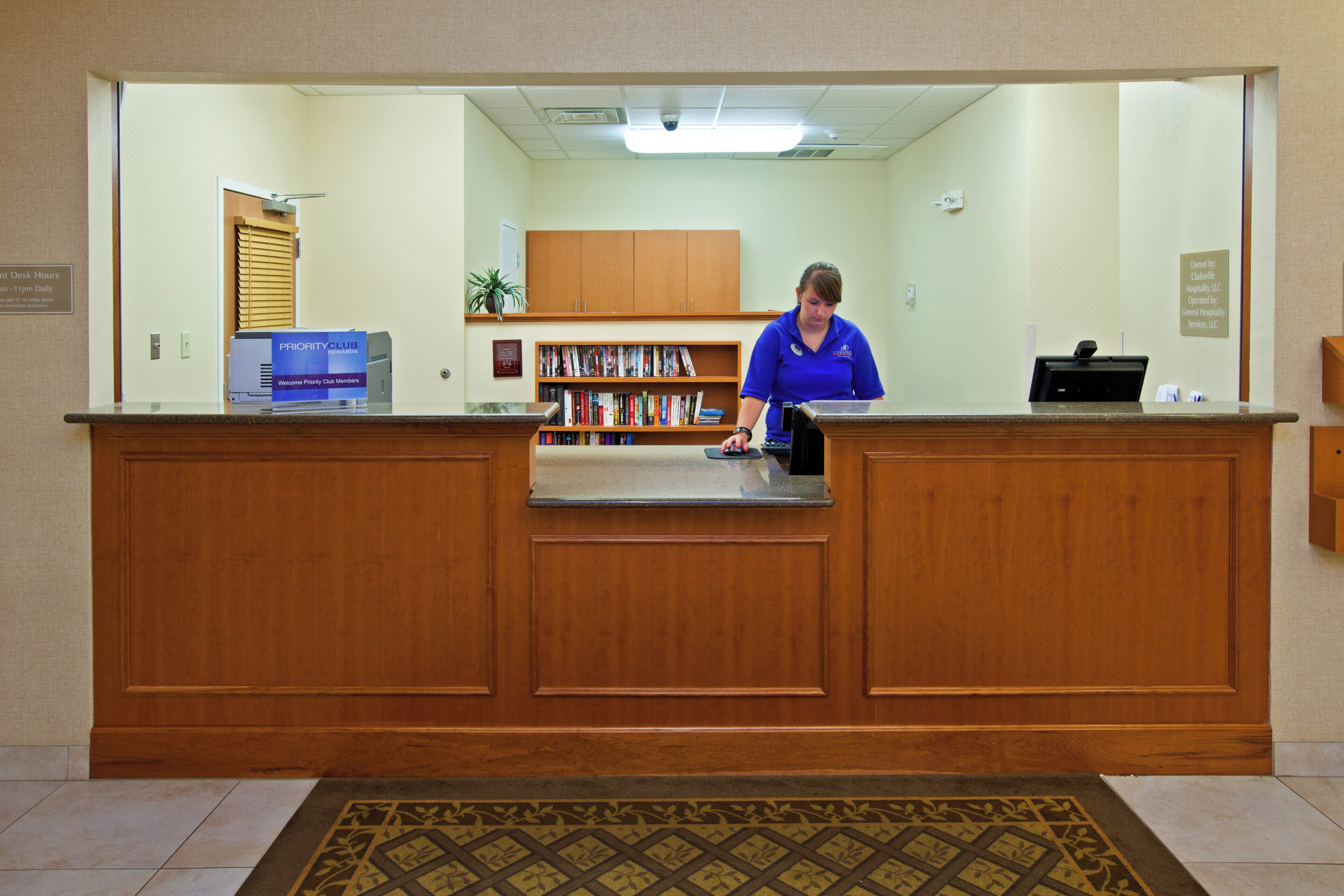 A reception desk with a wooden counter, a computer, and a bookshelf filled with books.