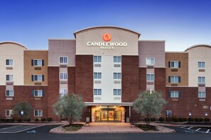 A multi-story hotel with a prominent "Candlewood Suites" sign, featuring a brick facade and a central entrance with glass doors.