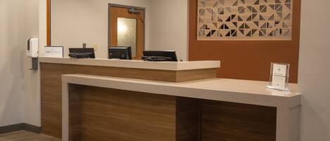 A reception desk with a wooden counter, a glass partition with geometric patterns, and a sign indicating a no clean promise.
