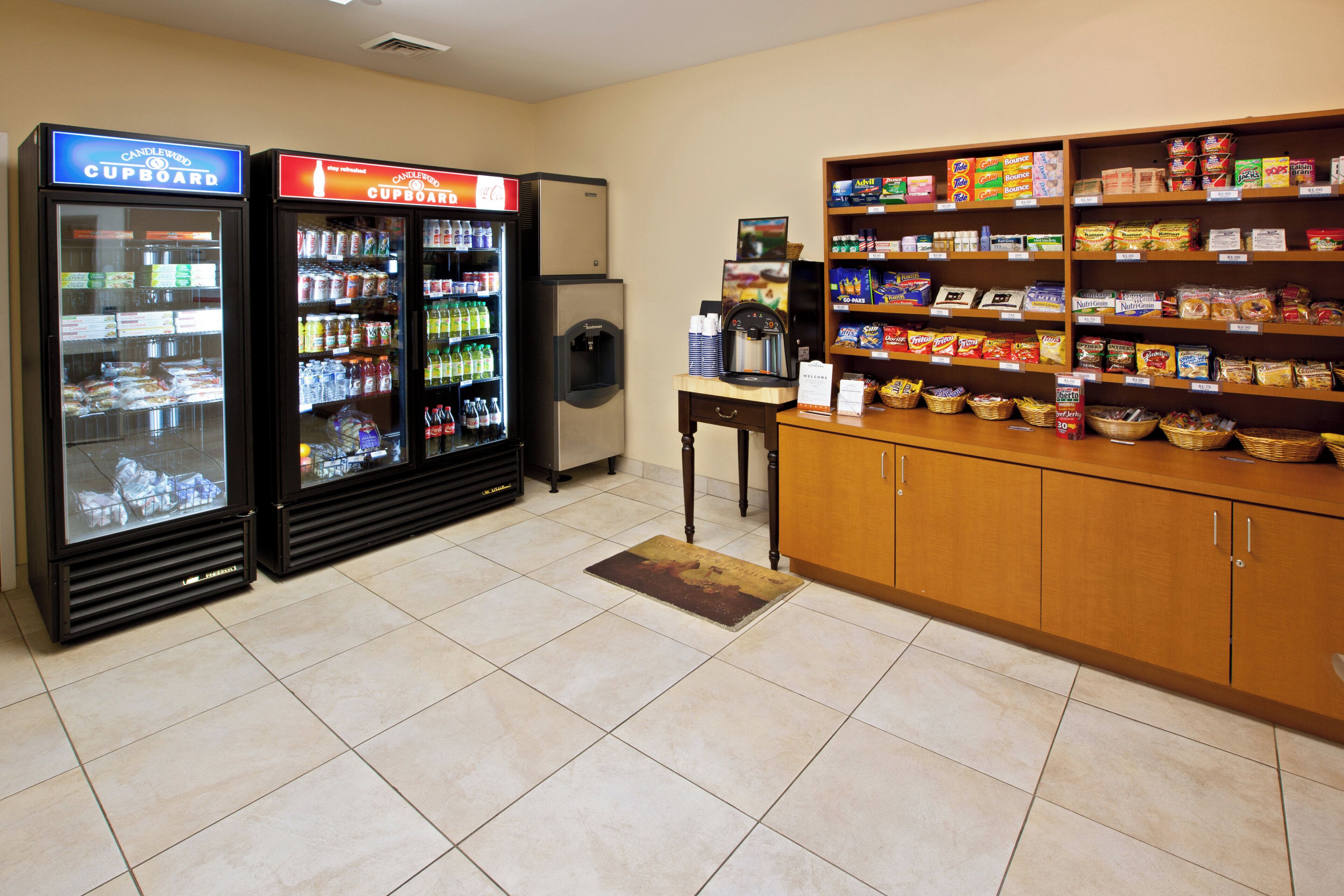 A kitchenette area with a refrigerator, a vending machine, and a shelf stocked with snacks.
