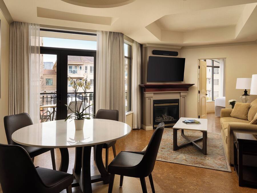 Ein Hotelzimmer mit Essbereich, einer Couch, einem Kamin und einem Fernseher.
