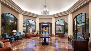 A spacious lobby with a chandelier, seating area, and large windows offering views of the outside.