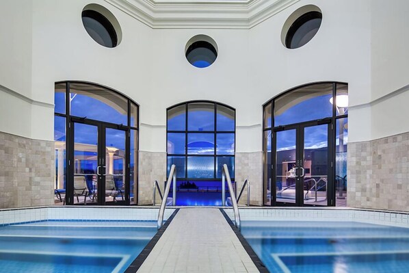 Une piscine intérieure avec de grandes fenêtres offrant une vue sur le ciel.