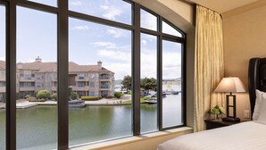 A hotel room with large windows overlooking a body of water, a marina, and a multi-story building.