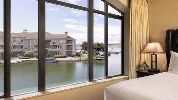 A hotel room with a large window, a bed, a nightstand, and a lamp.