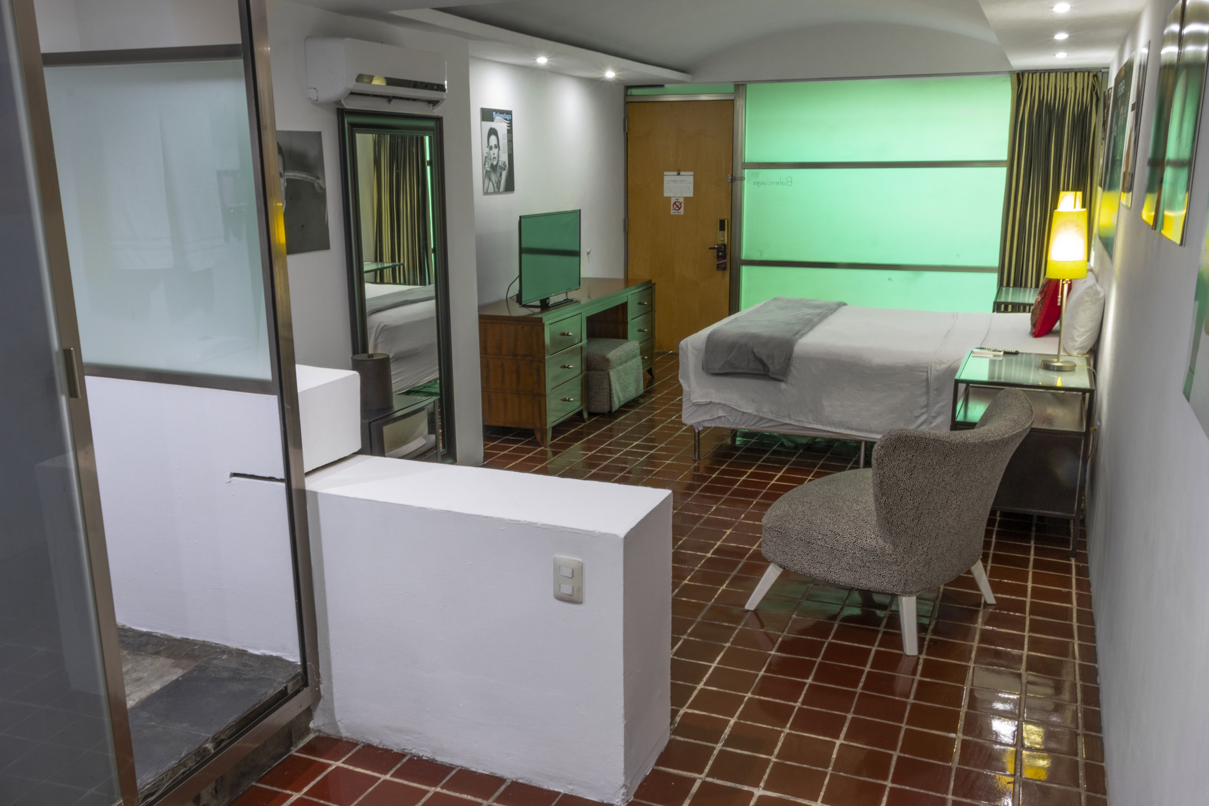 Een hotelkamer met een bed, een bureau met lamp, een stoel, een dressoir en een televisie.