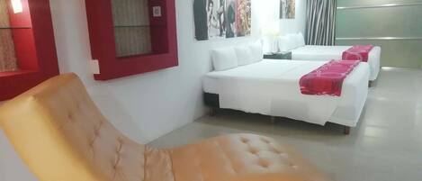 A hotel room with a large bed, a sofa, and a window with red trim.