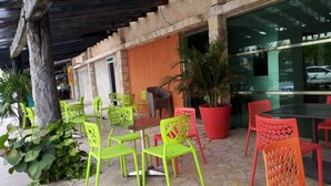 Un espace extérieur aménagé avec des chaises vertes et rouges, une table et des plantes en pot.